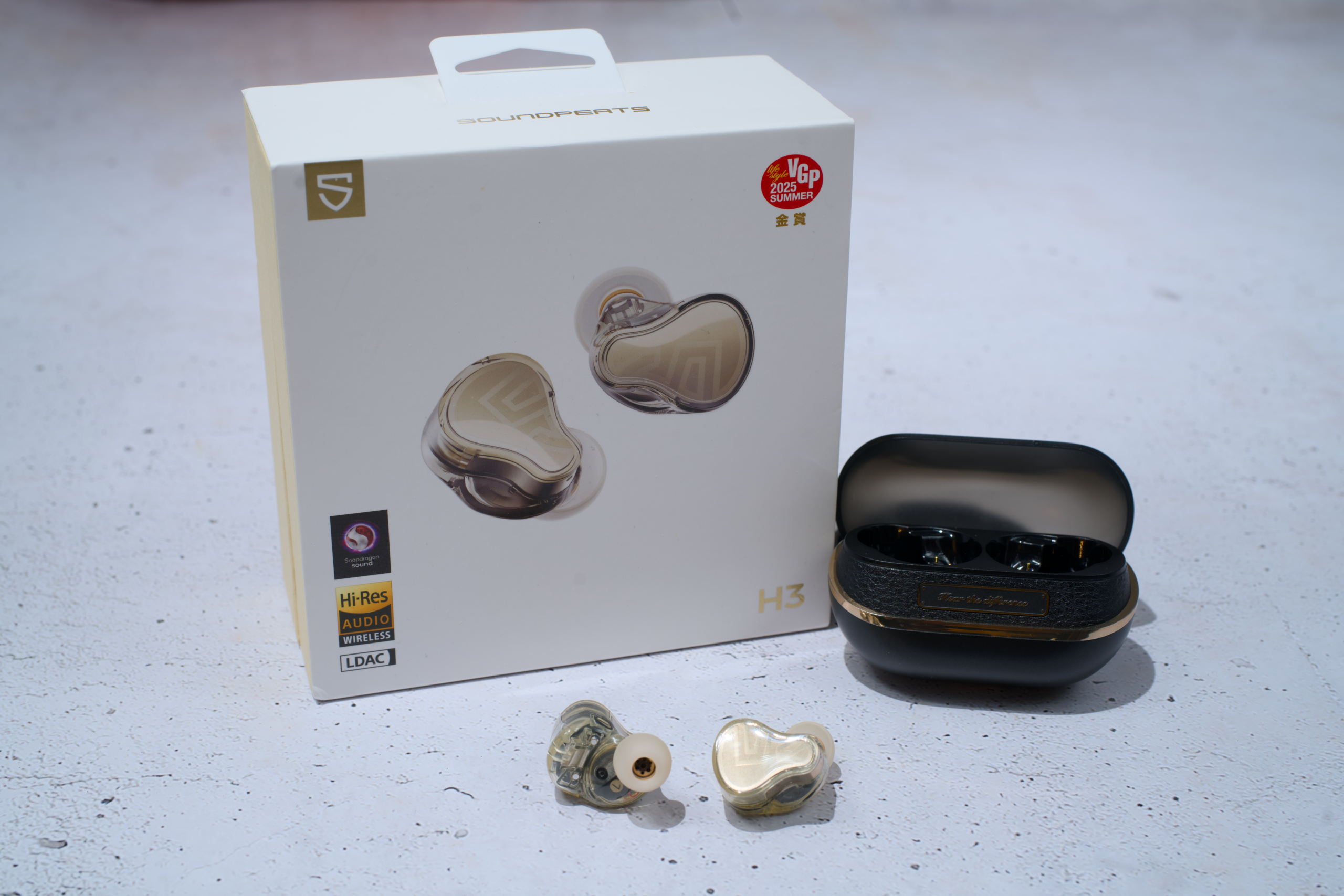 SoundPEATS H3 earbuds in an open charging case beside the retail box